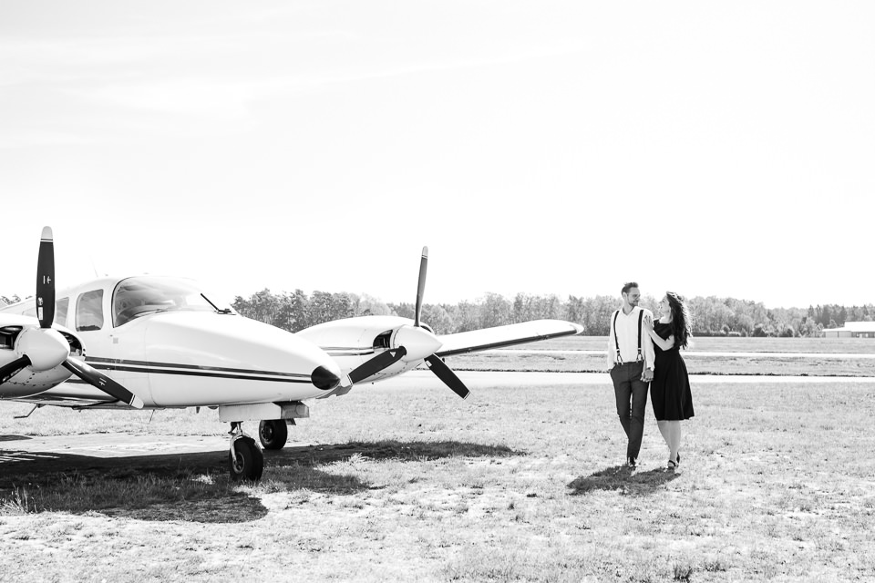 schwarz weiß Foto eines Pärchens neben Flugzeug