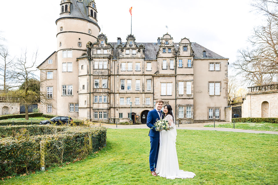 Hochzeitspaar steht im Schlosspark vor Schloss Detmold