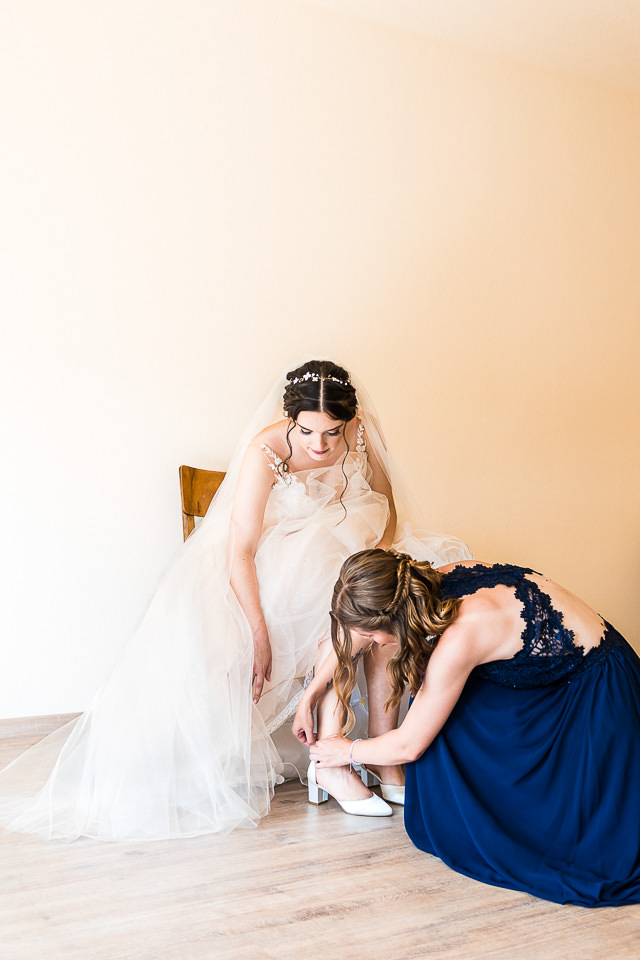 Schwester hilft Braut in die Schuhe