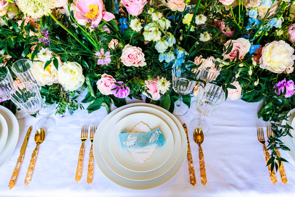 Goldenes Besteck ziert die Hochzeitstafel. Pastellige Blumen im französischen Stil wurden stilvoll drapiert.