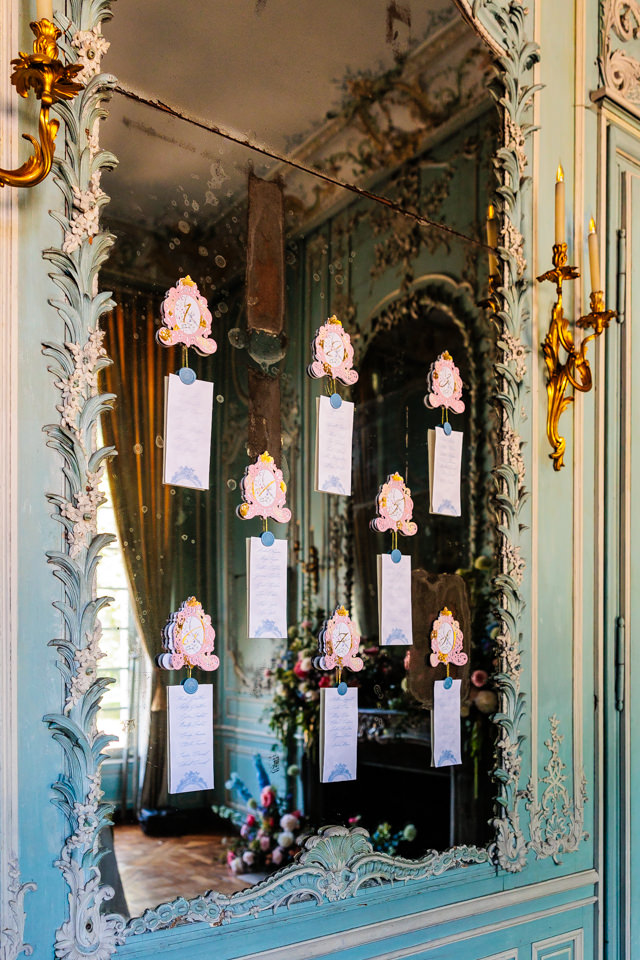 Filigraner Sitzplan hängt dekorativ am Wandspiegel des französischen Hochzeitsschlosses.