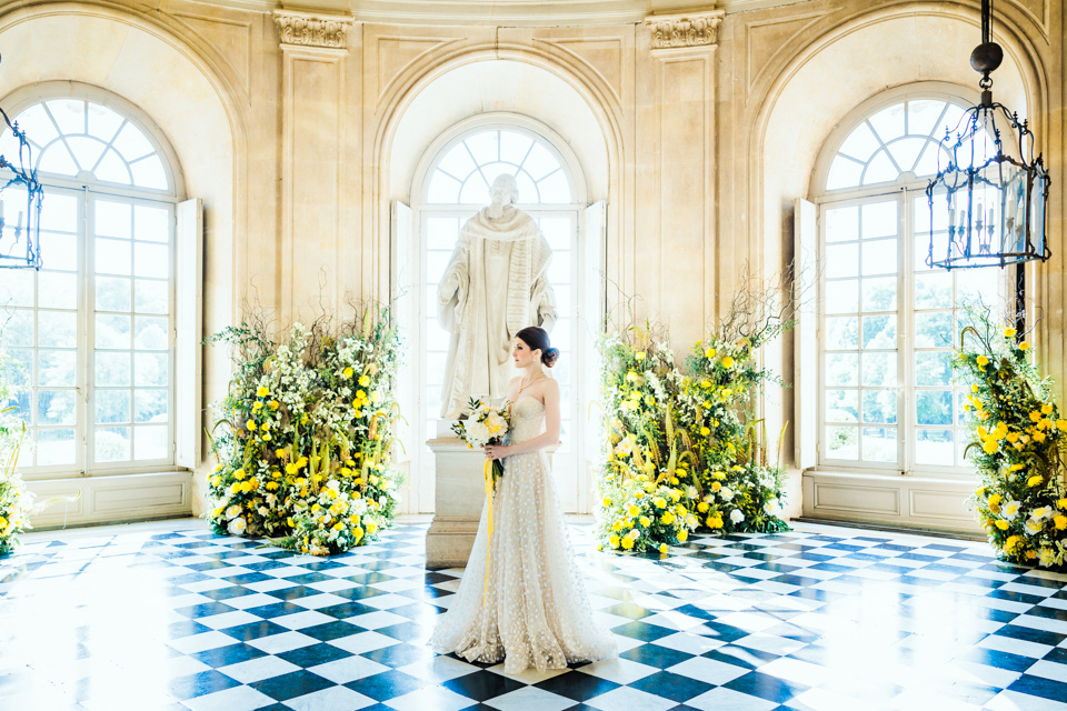 Die Braut steht bei ihrem Bridal Shooting in einem Raum, hinter ihr eine große, weiße Statue. Der Fußboden weist ein Schachbrettmuster auf.