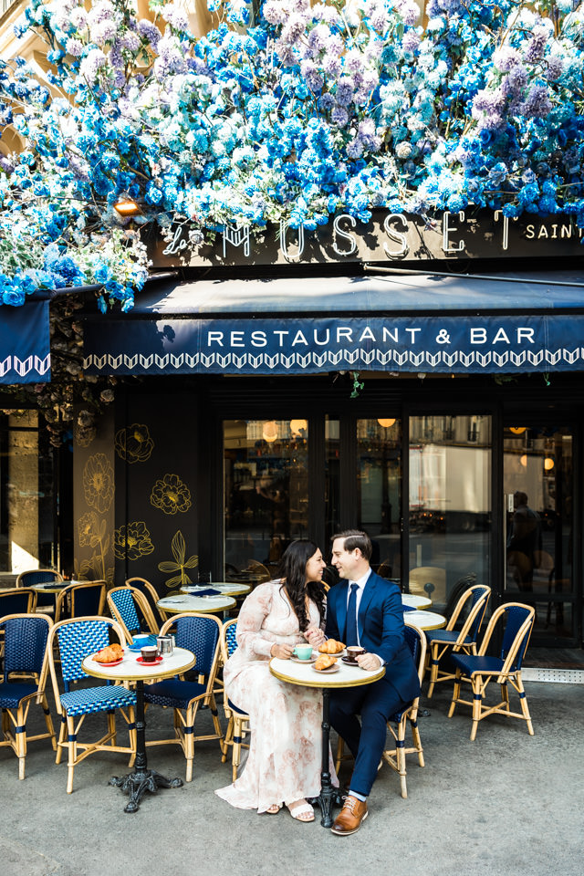 Blaue Blumen schmücken das Dach eines Cafés in Paris beim Paarshooting.