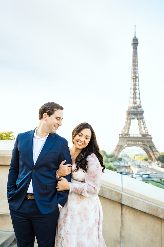 Pärchen ist beim Paarshooting in Paris vor dem Eiffelturm zu sehen. Er schaut sie glücklich an.