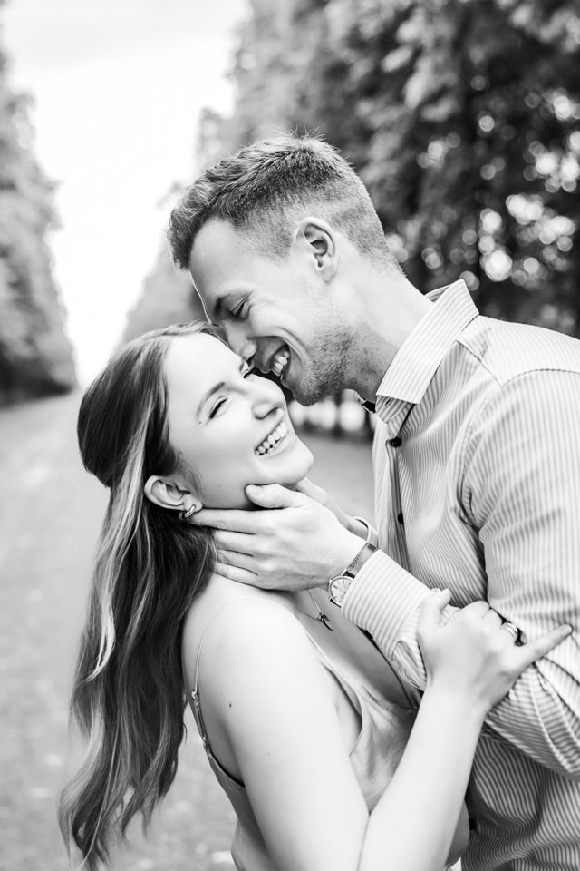 Paar küsst sich und lacht herzlich beim Fotoshooting im Georgengarten Hannover.
