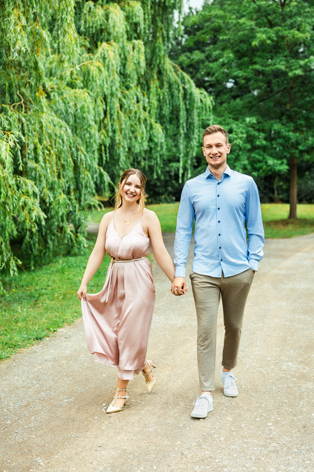 Das Paar spaziert beim Fotoshooting gemeinsam durch den Georgengarten Hannover.