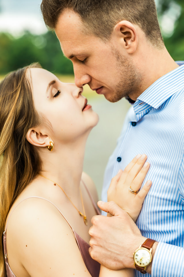 Paar küsst sich beim Fotoshooting im Georgengarten Hannover und präsentiert dabei den goldenen Verlobungsring.
